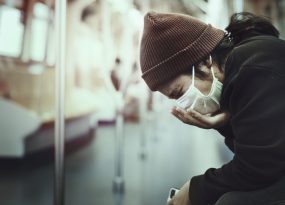 Sick woman in a mask coughing in public during coronavirus pandemic